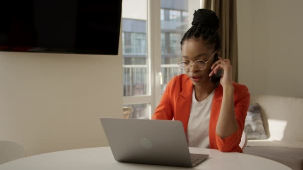 Νεαρή Αφροαμερικανή μιλάει στο τηλέφωνο από ένα γραφείο στο σπίτι. — Αρχείο Βίντεο