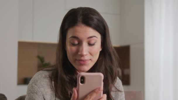 Крупный план - молодая белая женщина приветствует своих друзей по видеосвязи с помощью розового смартфона — стоковое видео