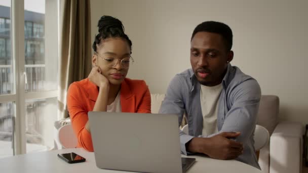 Casal família afro-americana discutindo seus planos usando um computador portátil em casa — Vídeo de Stock