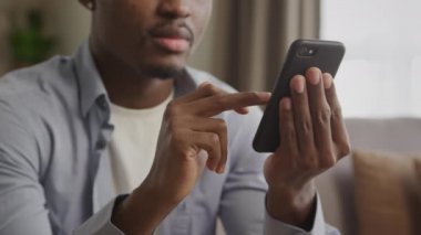 Tanımlanamayan Afro-Amerikan genç bir adamın siyah akıllı bir telefonu aşırıp internette dolaşırken gülümsemesine yakından bakın.