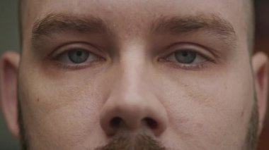 Mavi gözlerini yavaş çekimde açan genç beyaz bir adamın yakın çekimi.