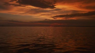 Gün batımında akan bir nehrin üzerinde yavaş çekimde dramatik bir gökyüzü var.