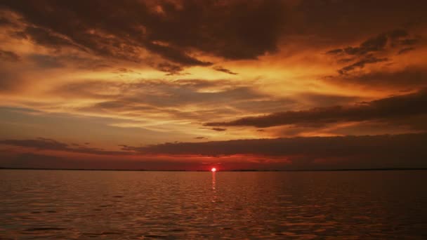 Altın saat boyunca güneşin kırmızı bir günbatımında nehrin üzerinde ağır çekimde batışını gösteren yavaş bir kamera var. — Stok video