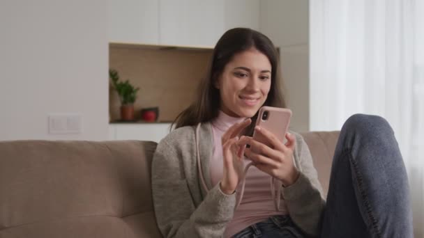 Junge erwachsene Frau surft mit ihrem Smartphone im Internet und zeigt eine Vielzahl von Reaktionen auf den Inhalt — Stockvideo