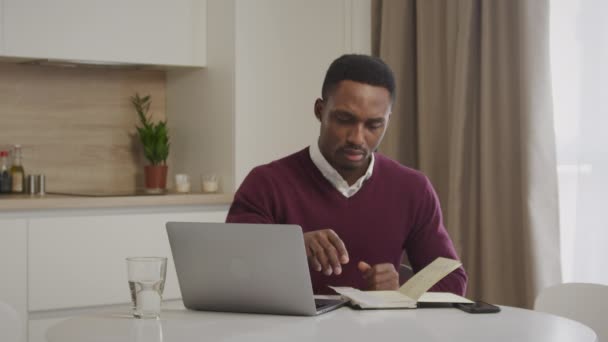 Jovem afro-americano checando suas contas e administrando os gastos domésticos — Vídeo de Stock