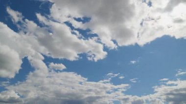Dağılmış kümülüs bulutlarıyla dolu canlı mavi gökyüzü doğa ve hava teması için ideal manzaralı ve barışçıl bir bulut manzarası oluşturuyor..