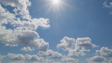 Pofuduk kümülüs bulutlarıyla dolu açık bir günde, güçlü güneş ışığı altında hareket eden parlak mavi bir gökyüzünün zaman akışı..