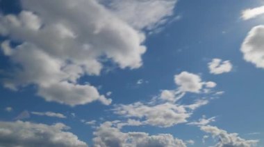 Hızlı hareket eden beyaz bulutlarla dolu canlı bir mavi gökyüzü, dinamik bir bulutun içinde doğal hava modellerini ve hareketlerini gösteriyor..