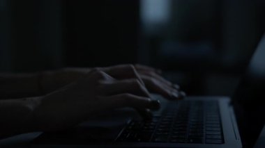 Bir karartma sırasında loş bir odada dizüstü bilgisayarda yazı yazan eller sadece ekranların parlaklığıyla aydınlatılıyor..