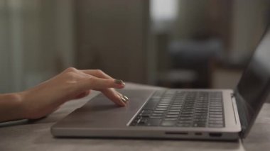 Bir insan parmaklarını yumuşak ışıklı bir odada dizüstü bilgisayarda kaydırıyor, modern çalışmaları veya tarama faaliyetlerini yakından gösteriyor.