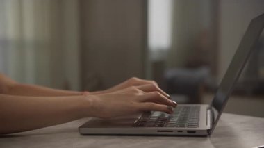 Evde dizüstü bilgisayarda yazarken, gün ışığında sakin ve üretken bir çalışma ortamı yaratırken yan görünüm.