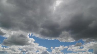 Mavi gökyüzünde toplanan kara fırtına bulutlarının dramatik zamanlaması yağmurun yaklaştığını ve hava koşullarının değiştiğini gösteriyor..