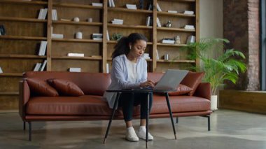 Modern ofis salonlarında dizüstü bilgisayar kullanan, uzaktan çalışan ya da yaratıcı iş yerindeki görevleri tamamlayan genç bir kadın..