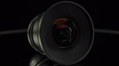 Koyu renkli yansıtıcı yüzeyde geniş açılı sinüs lensi ön cam, simetri ve sinematik optiği vurguluyor..