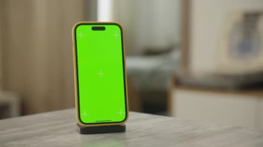 Parlak yeşil krom anahtar ekranlı modern akıllı telefon, dinamik model kullanımı için hareket eden bir kamera ile kapalı alanda çekildi.