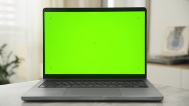Parlak yeşil renkli anahtar ekranlı modern bir dizüstü bilgisayarın ön görüntüsü, dinamik model kullanımı için doli yakınlaştırma efektiyle kapalı alanlarda çekildi.