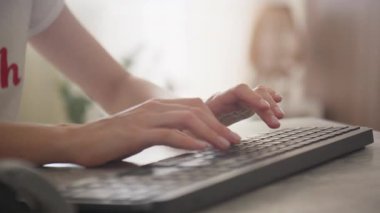 Kapalı mekan ışıklarıyla bilgisayar klavyesine yazı yazan eller günlük ofis işlerini, uzaktan iletişimi ve dijital üretkenliği gösterir.