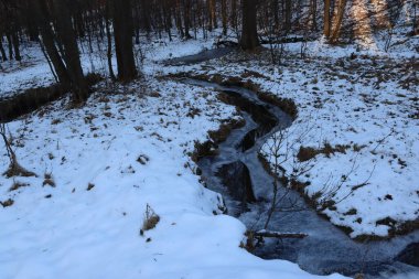 Donmuş deresi olan karlı bir vadi. Bir derenin kıvrımları.