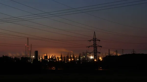 Bir fabrikanın gece fotoğrafı. Ön planda yüksek voltaj kutupları.