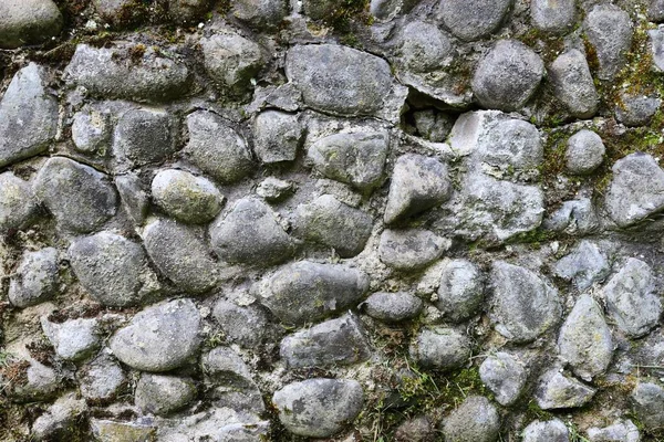 Old concrete stone wall overgrown with moss. Wall texture.