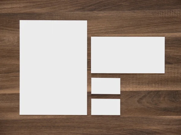 Λευκό χαρτί, φάκελος και επαγγελματικές κάρτες σε ξύλινα φόντο. — Φωτογραφία Αρχείου