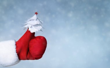 Noel Baba 'nın kırmızı eldivenini uzat başparmağında küçük beyaz bir noel ağacı olan 
