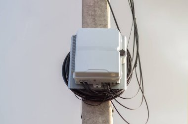 İçinde kablolar olan bir elektrik direğinin üzerindeki fiber optik kutu.