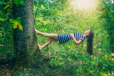 Güneş ışığının altında ağaçta yürüyen peri bir kız..