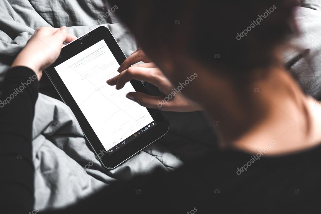 Young girl using tablet in bed