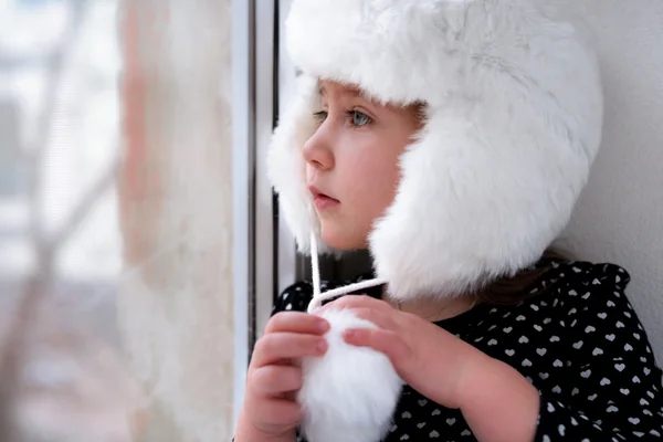 Una niñita congelada mirando por la ventana Imagen De Stock