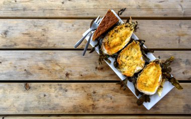 Ahşap bir masa üzerinde bir tabak içinde üç istiridye