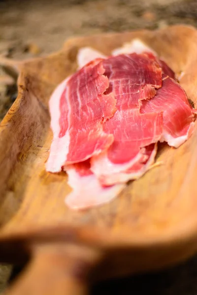 Slicing of italian dry-cured ham prosciutto. Toned image. Selective focus point — Stock Photo, Image