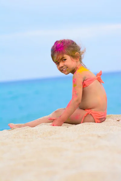 Cte giovane bambina con viso colorato, festa in spiaggia Foto Stock Royalty Free