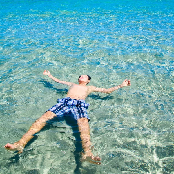 Joven niño feliz divirtiéndose en el agua de mar tropical clara. Concepto relajante — Foto de Stock