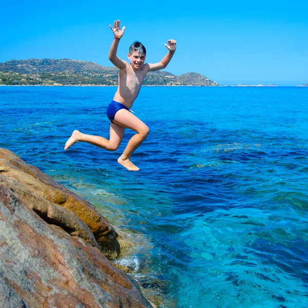 Young happy boy having fun on tropical beach, jumping into the air — Stock Photo, Image