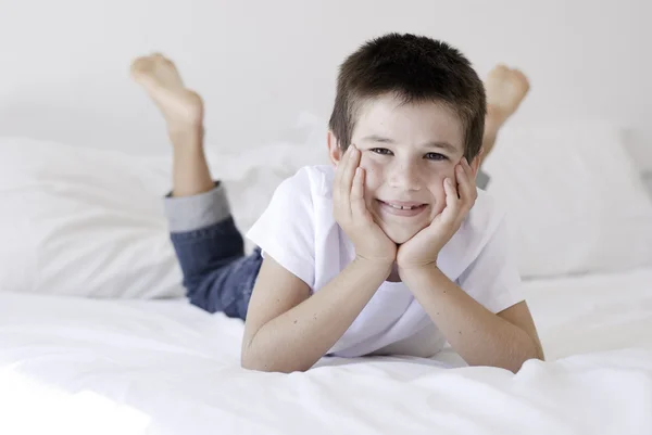 Jovem feliz posando em uma cama branca — Fotografia de Stock