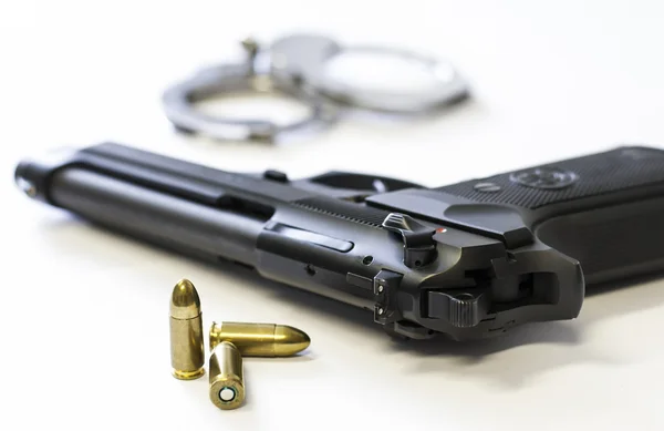 Silah, mermi ve beyaz arka plan üzerinde kelepçe