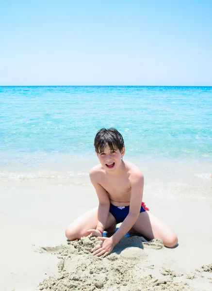 Jeune garçon heureux s'amusant sur une plage tropicale, jouant sur un sable blanc et de l'eau de mer claire — Photo