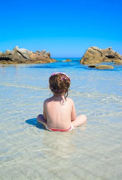 Kleines Mädchen sitzt auf dem Meer — Stockfoto