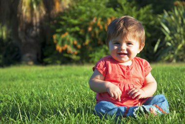 küçük kız çimenlerin üzerinde gülümseyen