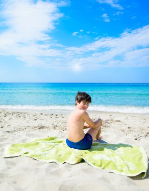 Küçük çocuk oturuyor.