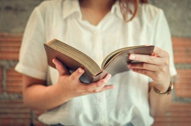 Genç bir Hıristiyan kadın Pazar günü odasında kitap okuyup ders çalışıyor..