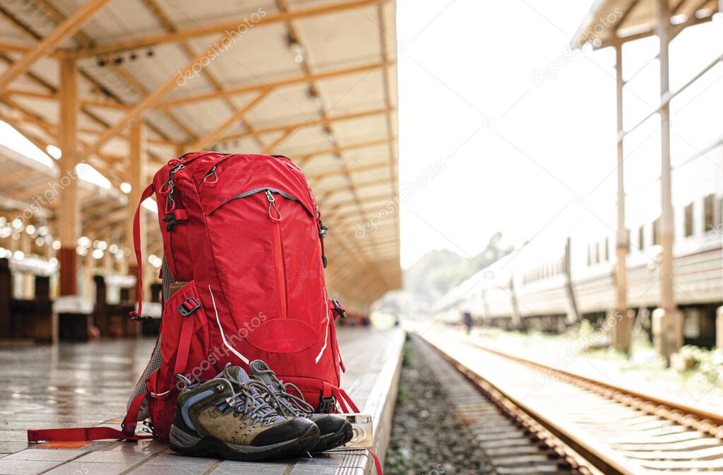 Map in backpack, camera, shoes and personal belongings in a train station with travelers.