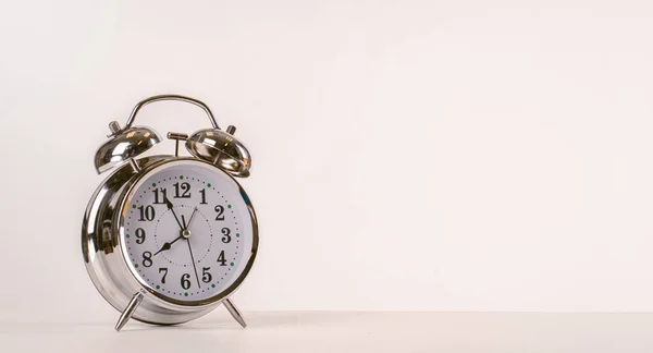 White background with silver ancients clock on the table