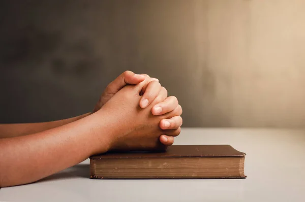 Christian life crisis prayer to god. Man Pray for god blessing to wishing have a better life. man hands praying to god with the bible. believe in goodness. Holding hands in prayer on a wooden table.