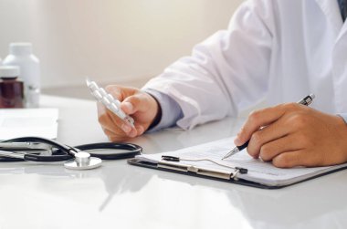 Doktor ilaç kağıdını tuttu ve ARV uyuşturucu listesinin geçerliliğini kontrol etti ve araştırma sonuçlarına kaydetti..