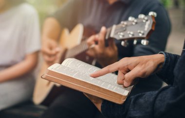 Arkadaşı gitar çalarken genç bir çocuk İncil okur. Tanrı 'ya ibadet ederken küçük bir Hıristiyan grubu ya da kilisedeki bir kavram grubu....