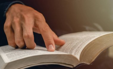 Genç adam İncil 'den bir konuyu işaret ediyor ve Tanrı' nın kutsamasını almak için pazar günleri İncil okuyor..