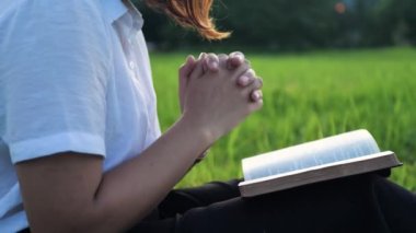 Dua eden bir kadın, Tanrı 'yla dua ederek konuşur. Elleri İncil 'de Tanrı' nın kutsaması için karanlık bir odada dua ediyor..