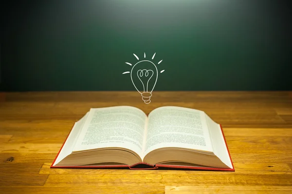 Libro aperto su tavolo con lampadina per idea concept — Foto Stock